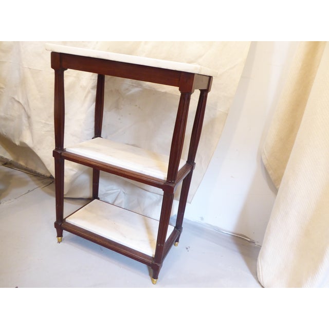 This Louis XVI style end table with marble top and shelves, has reeded tapered legs and bronze sabots. The height between...