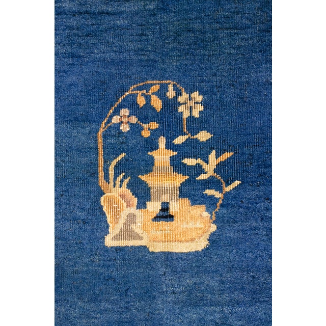 Antique Chinese peking rug, circa 1920–1940, featuring a rich sapphire blue field centered with a traditional floral...