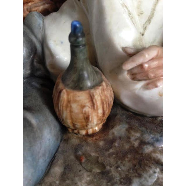 A detailed, hand-painted vintage Italian porcelain sculpture depicting an elderly man resting inside a rustic, ruined...