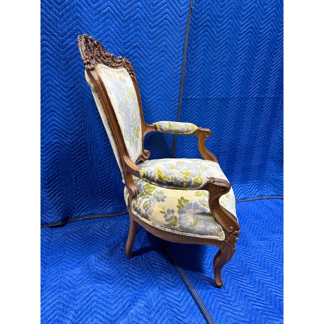 French Louis XV style armchair featuring a hand-carved walnut frame and floral upholstery. Similar pieces are often...