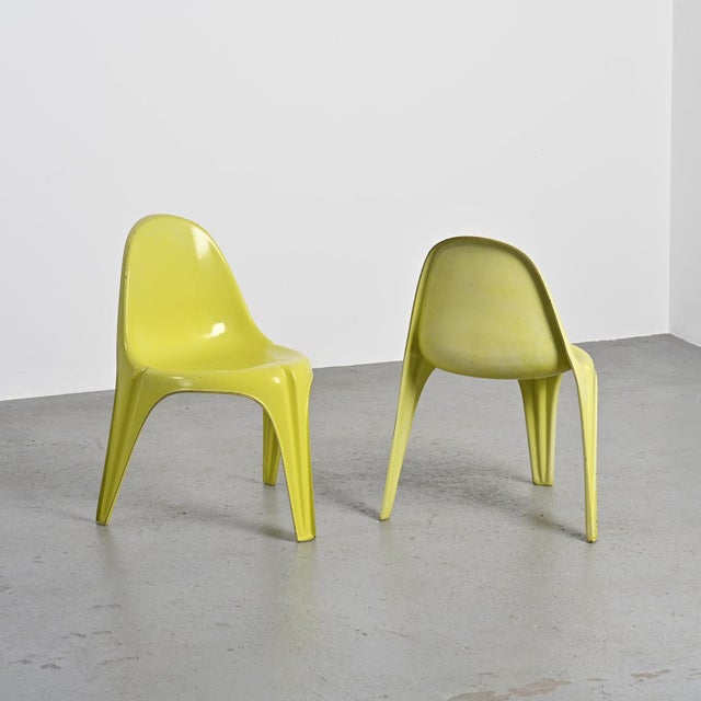 Pair of tripod chairs made entirely of fiberglass, finished in a vivid, deep yellow lacquer. Their sculptural silhouette...