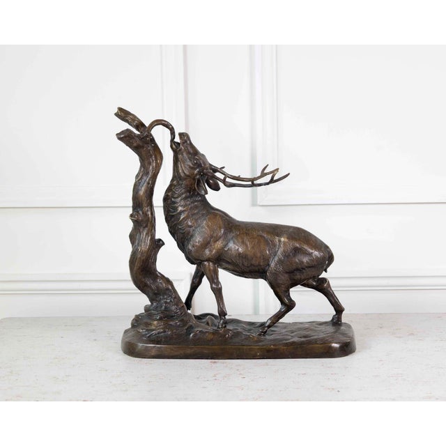 A beautiful and expressive animal sculpture depicting a stag in a rutting pose, standing upright against a tree trunk, in...