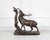 A beautiful and expressive animal sculpture depicting a stag in a rutting pose, standing upright against a tree trunk, in...