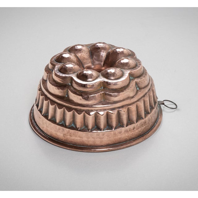 Antique English copper bundt cake mold with four tiers of design with tinned lining and metal ring for hanging.