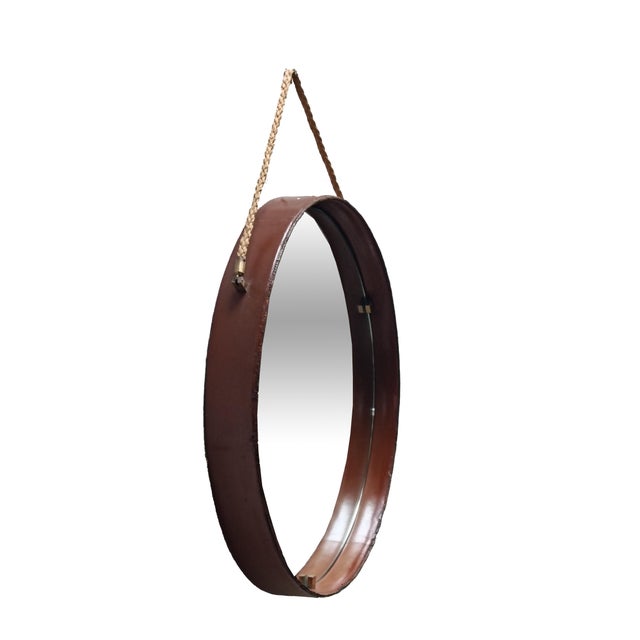 An Italian-made mirror produced in the 1950s by Pizzetti. Circular metal frame covered in cognac-brown leather. Brass...