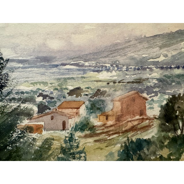 Original watercolor on paper depicting a broad rural landscape with hillside buildings, trees, a winding road and distant...