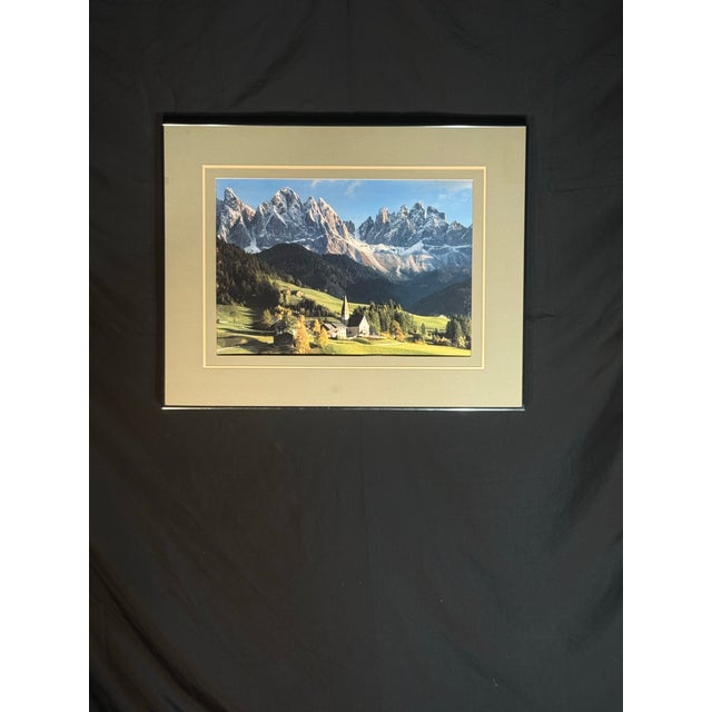 Elegant framed landscape photograph featuring a scenic Dolomites mountain range with snow-capped peaks, a lush green...