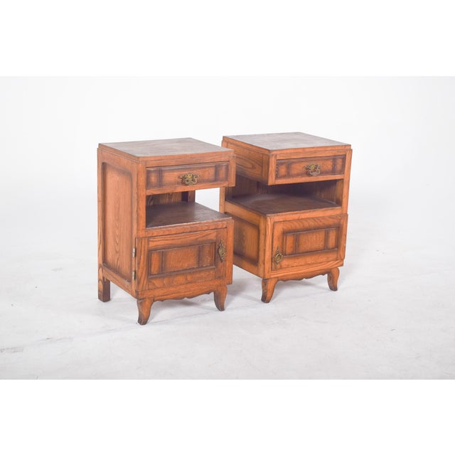 Pair of oak bedside tables. Top drawers with metal handles, a central open niche and a bottom door with a beaded frame and...