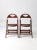 A distinctive pair of antique wooden folding chairs, dating to the early 20th century. The chairs feature gracefully...
