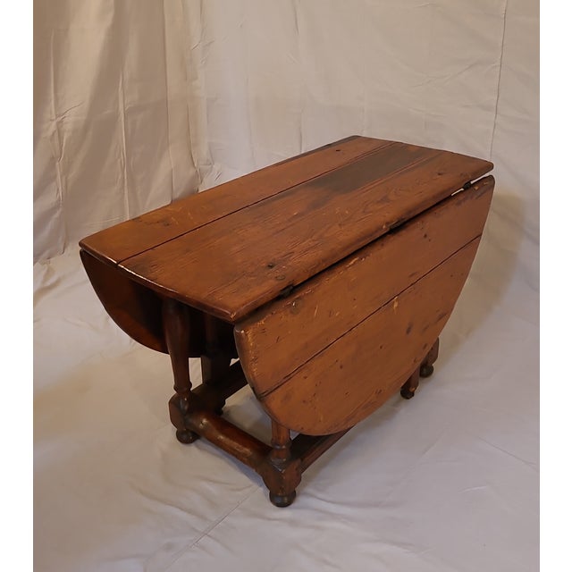 This is a gorgeous antique drop leaf table from the 18th century. The turned legs are a rich colonial style. The top has a...