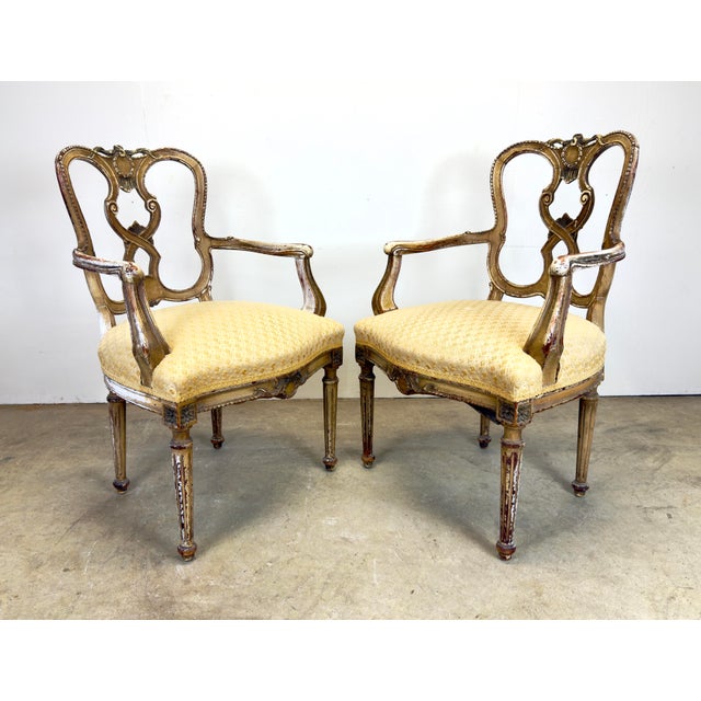 A pair of beautifully distressed French Louis XVI / Directoire style armchairs showing tan and white paint and mahogany...