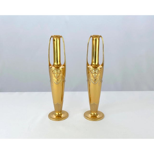 An antique two-handled gilt metal vase pair in the neoclassical style by Orivit-Metallwarenfabrik AG of Germany, dating to...