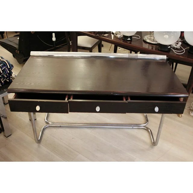 This writing desk was produced in Italy during the 1970s and features a tubular chrome structure and a wooden veneer top.