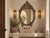 A beautiful late 20th century mirror with crest decoration on top. This vintage mother of pearl inlaid mirror has an oval...