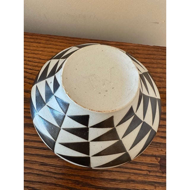 A striking sculptural ceramic vessel featuring a bold black-and-ivory geometric pattern. The rounded, flattened...