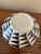 A striking sculptural ceramic vessel featuring a bold black-and-ivory geometric pattern. The rounded, flattened...