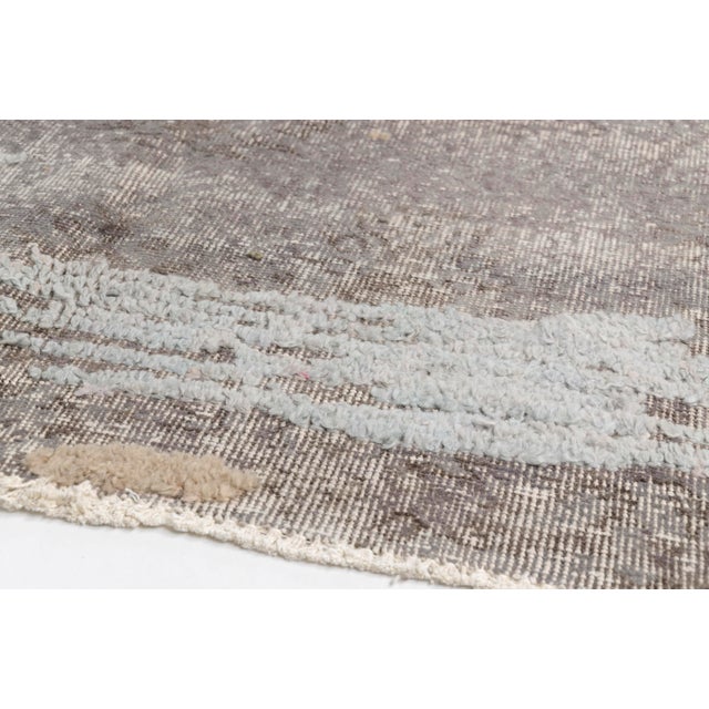 This is a vintage Turkish Oushak rug from the Mid 20th Century. The piece was hand-knotted.