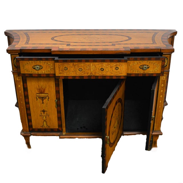 A statement in neoclassical elegance, this Castilian Imports sideboard cabinet is richly adorned with hand-painted urn...