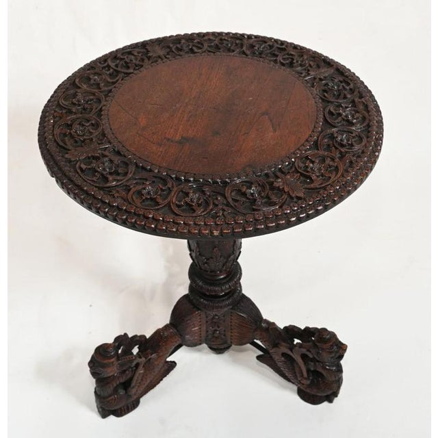 A round highly carved Burmese table on a tri formed base Circa 1840 Legs terminating in mythical Asian characters....