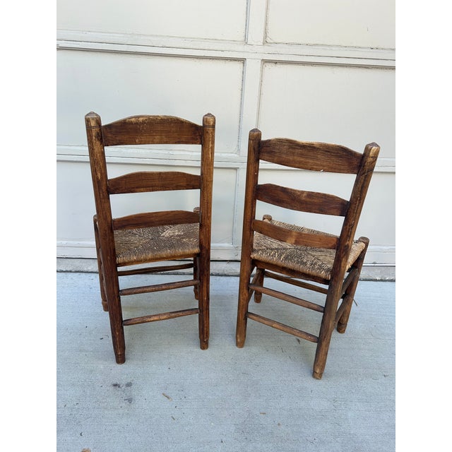 This is a remarkable pair of antique American ladder-back side chairs, dating back to the 19th century. Crafted from rich,...