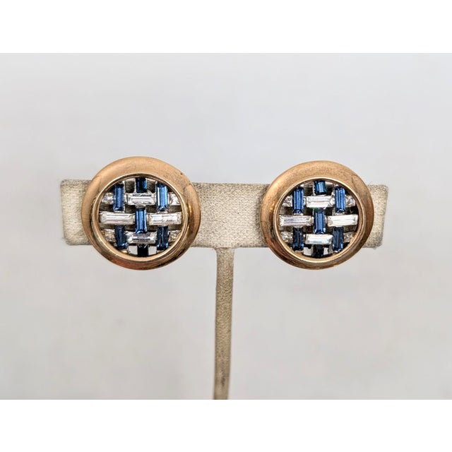 Early 1950s goldtone around the edges and rhodium plated in the center round hatched baguette faux-sapphires and clear...