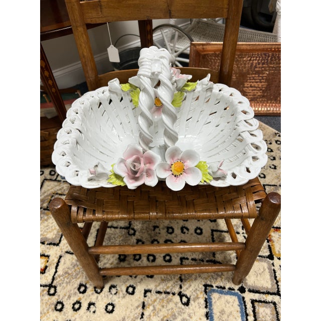Intricately woven porcelain basket with flowers. The delicate petals are in white, pink and a touch of gold with green...