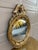 A Federal-style giltwood convex mirror crowned with a carved eagle, its wings outstretched above a laurel motif—an...