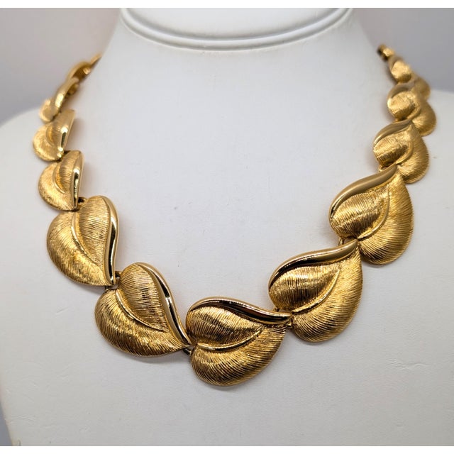 1982 goldtone graduated articulated textured heart shaped leaves collar necklace with fold over clasp. Marked "Napier" in...