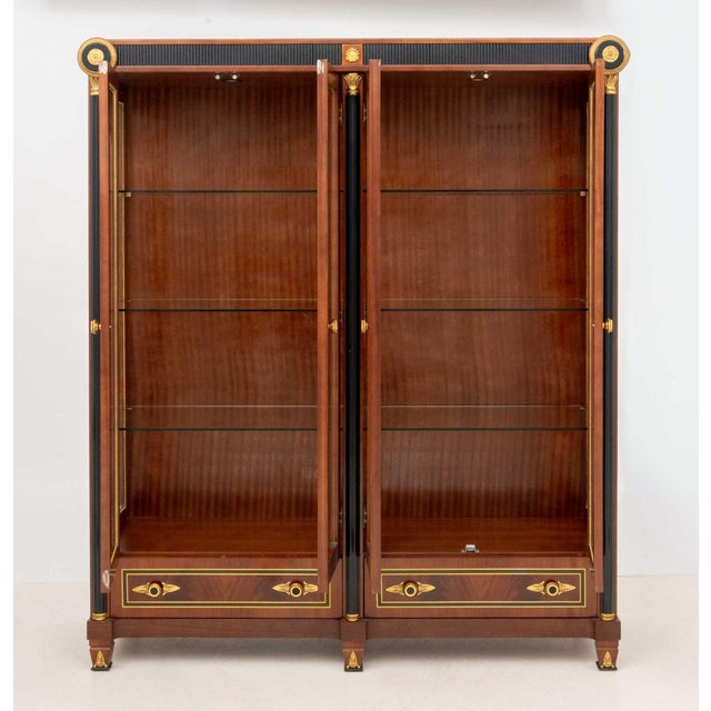 Empire Style Gilt Metal Mounted Mahogany Vitrine Cabinet, with two glass-paneled two-door compartments opening to glass...