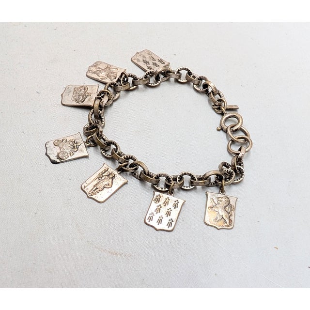 Late 1930s goldtone coat of arms charms bracelet with spring ring clasp. Marked "Monet Jewelers." Measures: 7.25 inches...