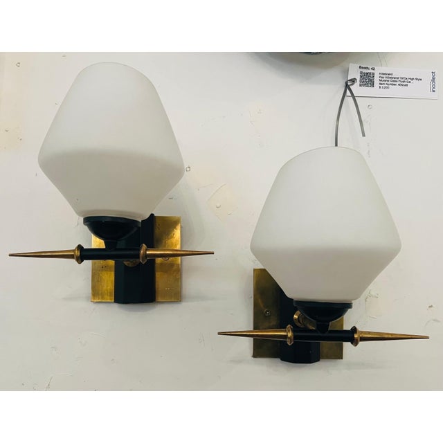 A wonderful pair of 1960s French sconces composed of brass horned and black enamel fixtures with white glass shades. Rewired