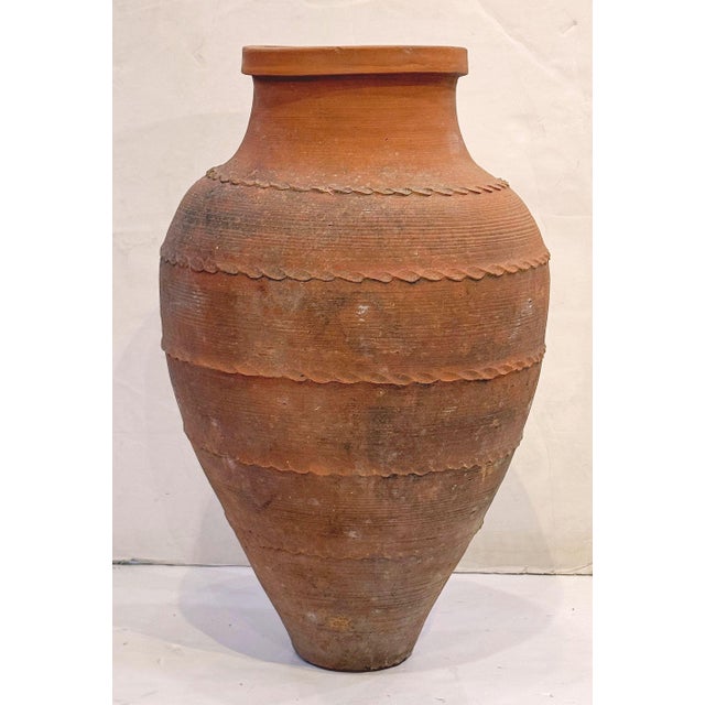 A handsome Greek terra cotta garden urn pot (Amphora) or oil jar, featuring a ridged, cylindrical body and functional as...