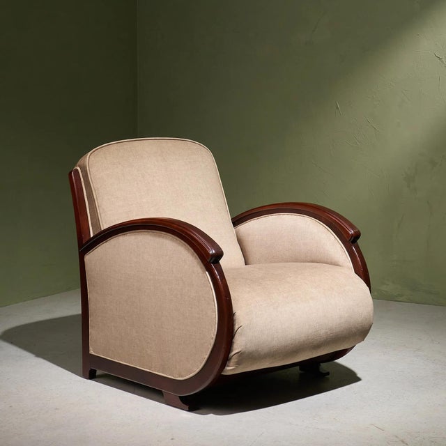 An original Art Deco lounge chair from the 1930s, re-upholstered in an ivory-toned fabric that highlights the sculptural...