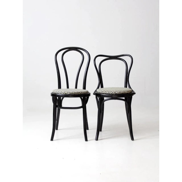 This is a pair of vintage painted bentwood cafe chairs. The mis-matching, matching bistro chairs feature a black painted...