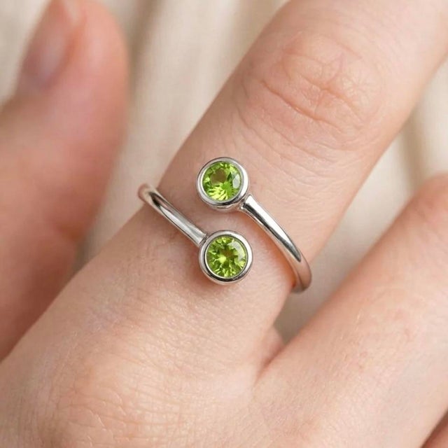 This modern and elegant open ring features vibrant Peridot gemstones, celebrated for their fresh green brilliance and...