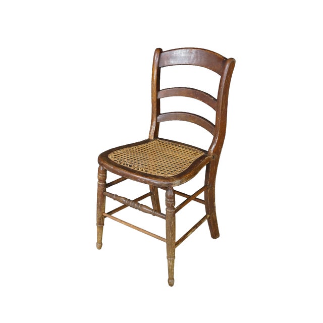 A charming pair of antique American primitive ladder-back side chairs beautifully exhibits the rustic simplicity and...