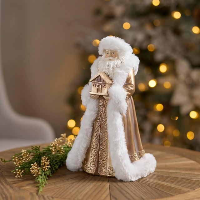 Add a touch of elegance to your holiday décor with this Santa Figurines with House in Gold and White (Set of 2). Dressed...