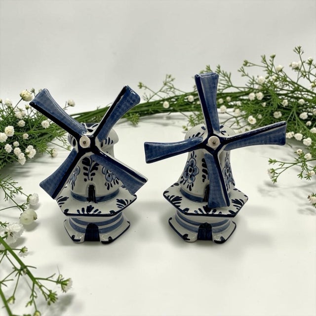 A pair of vintage blue and white ceramic Dutch windmill figurines crafted in the traditional Delft Blue style. They...