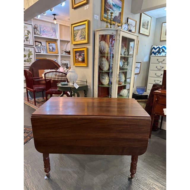 This is an American Antique Drop Leaf table. The wood is mahogany. The style is of Victorian era. The legs are carved...