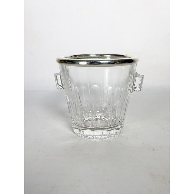 An elegant ice bucket made of clear molded glass, enhanced by a silver-plated metal rim. Dating from the 1970s, this piece...