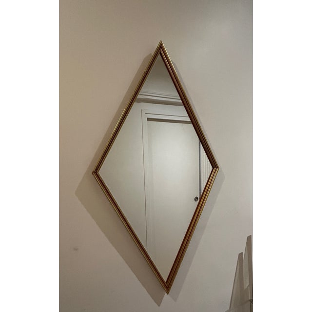 Mirror with a rare diamond shape and a burgundy and gold wooden frame.