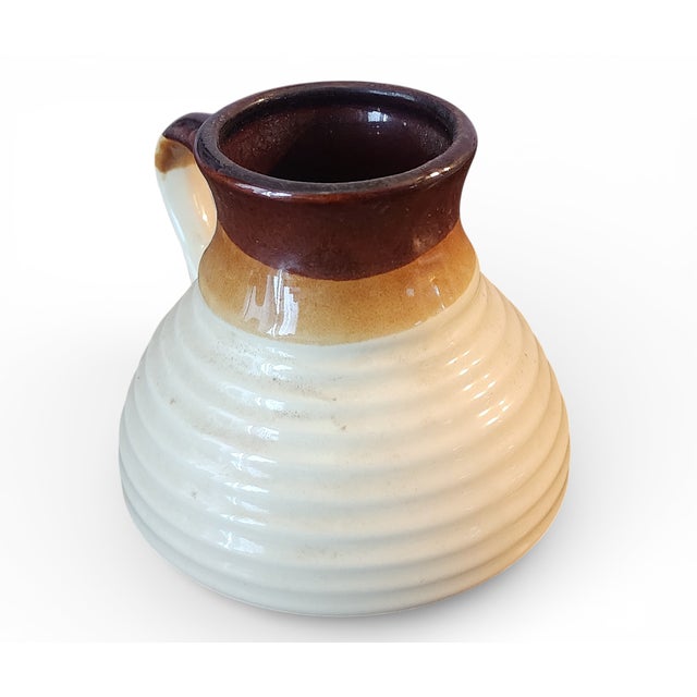 This is a great looking vintage ribbed stoneware art pottery pitcher. Brown glaze to cream ribbed body with single handle....