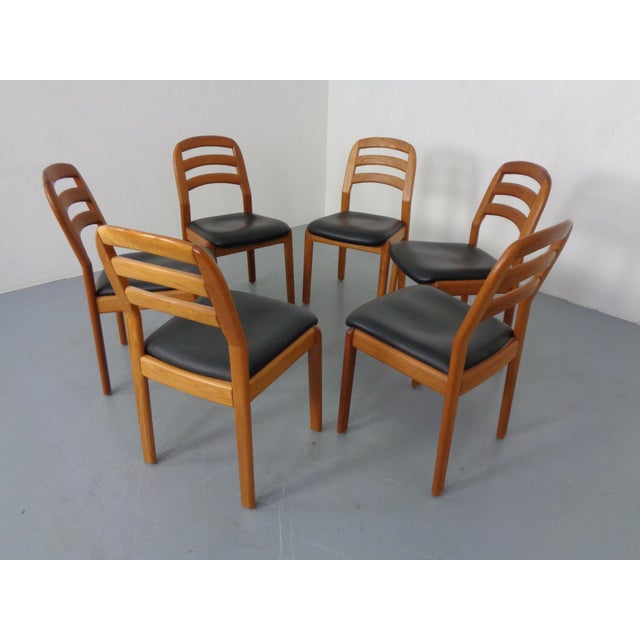 Set of 6 dining chairs in solid teak by Dyrlund. The seats are upholstered in black leather. This piece has an attribution...