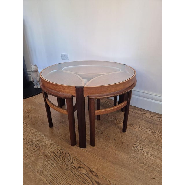 A striking 1960s Nathan Trinity Model 5614 teak coffee table with three nesting tables, combining sculptural mid-century...