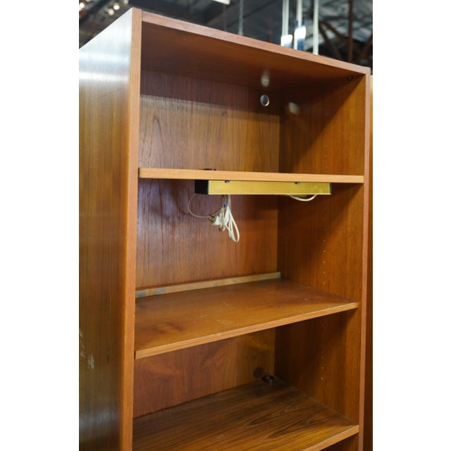 A Danish Modern Bookshelf teak; two sections, the upper section with a light affixed to one shelf, and with circular cut-...