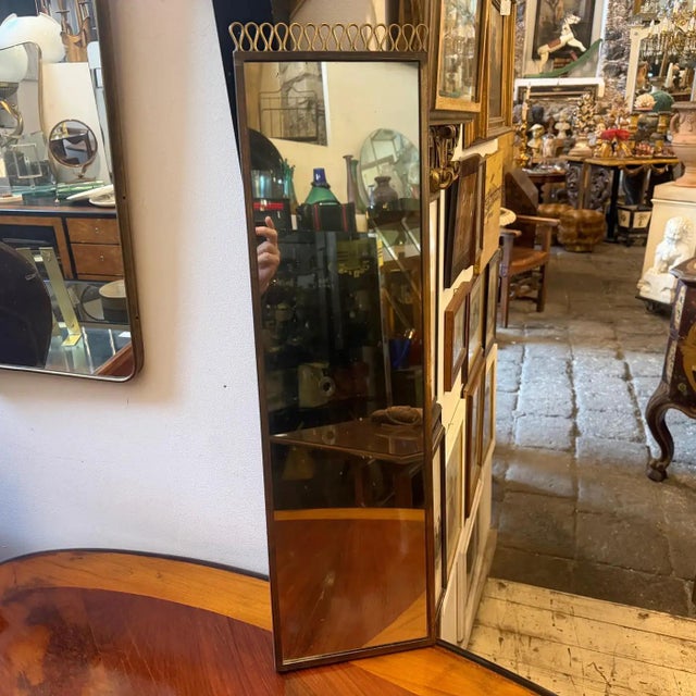 This elegant 1950s Italian Mid-Century Modern wall mirror features a refined rectangular silhouette heavily attributed to...