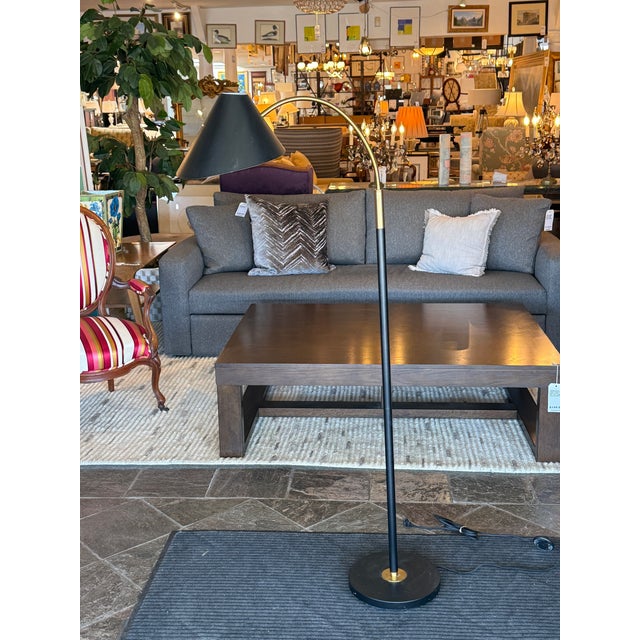 Design Plus Gallery presents an Arching Floor Lamp from Crate & Barrel. The floor lamp has a black base with a black stem...