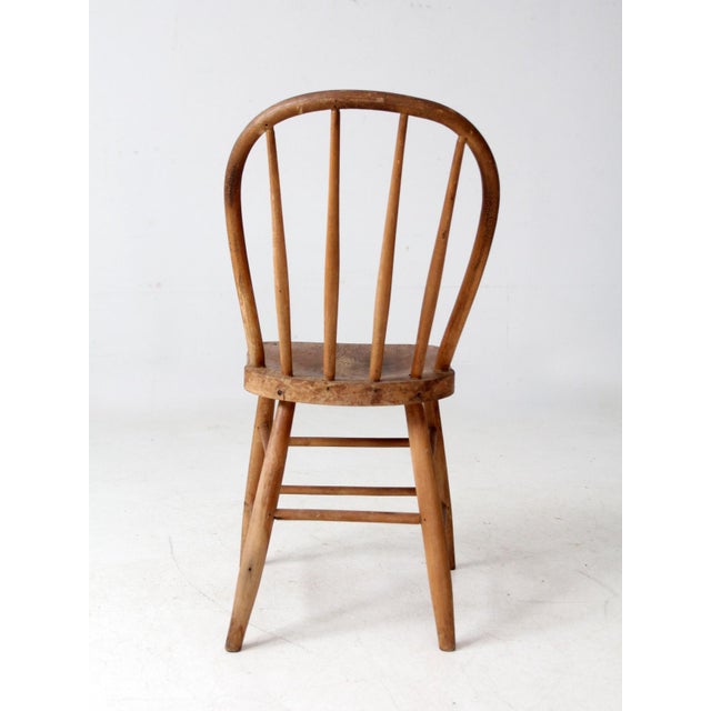 Antique wooden bow back Windsor chair featuring a curved rail, tapering spindles, and a shaped seat. The simple silhouette...