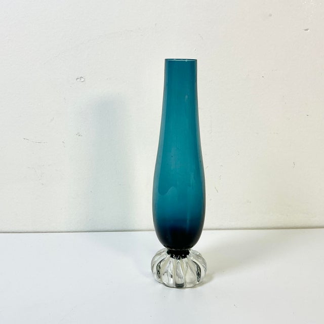A lovely Cerulean blue glass bud vase. From the Mid-Century the vase is blue cut to a clear pedestal base. The base...
