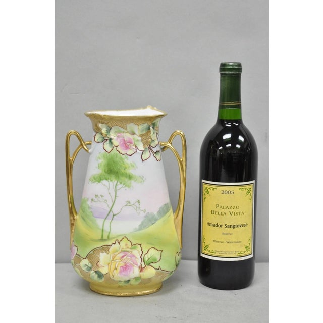 Antique Nippon Hand Painted Porcelain Twin Handle Gold Gilt Vase with Pink Flowers & Lake Scene. Circa Early 20th Century....